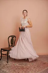 Vestido largo de tul plumetí en color rosa suave, con detalles de encaje bordado en el torso y volados en los hombros.