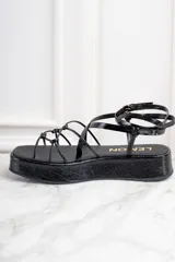 Sandalias negras de cuero charol con plataforma y tiras finas cruzadas.