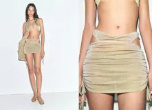 Minifalda de lúrex color dorado con diseño ajustado, fruncidos laterales y aberturas cut-out en la cintura con lazos ajustables.