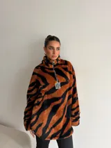 Buzo de peluche con diseño de estampado animal print de tigre, cuello alto con cierre frontal parcial y mangas largas.