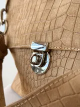 Cartera bandolera de cuero marrón con textura croco, solapa frontal, cierre metálico de giro plateado y correa de cadena con eslabones.