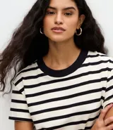 Remera de corte boxy confeccionada en algodón, con diseño de rayas horizontales en blanco y negro, cuello redondo en color negro contrastante y mangas cortas.