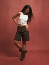 Short de jean color gris oscuro, tiro alto, con dobladillo ancho en el ruedo y corte recto que llega por encima de la rodilla.