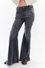 Jean de denim estilo oxford tiro medio, color gris con efecto acid wash. Presenta costuras decorativas en las piernas, botamanga desmechada y una hilera de botones laterales en la parte inferior de las piernas.