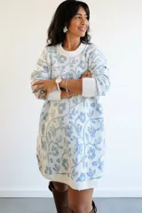 Suéter largo de punto con diseño floral en tonos blanco y azul, de corte holgado, cuello redondo y mangas largas con puños acanalados. Puede utilizarse como vestido tejido.