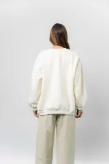 Buzo oversize de algodón frizado color beige, con cuello redondo, puños y cintura tejidos. Presenta un bordado tono sobre tono de Garfield en el frente.