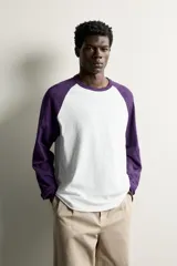 Remera manga larga de corte regular fit, con diseño estilo raglán en color blanco y mangas en color violeta oscuro.