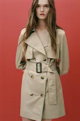 Trench confeccionado en mezcla de algodón color beige. Cuello solapa de muescas y manga larga ajustable con trabillas y botón. Bolsillos en delantero. Cinturón en mismo tejido ajustable con hebilla. Detalle de trabillas en hombros. Cierre frontal cruzado con botones.