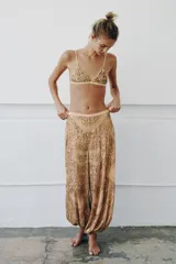 Pantalón de tiro medio con cintura elástica y bajo abullonado. Presenta un diseño con hilo metalizado y aplicaciones de abalorios y lentejuelas en toda la prenda.
