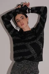 Sweater de tejido negro con rayas anchas en hilo brillante plateado, cuello redondo y calce holgado.