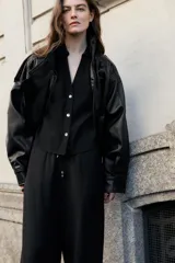 Camisa de cuello solapa y escote pico, color verde militar, con manga corta con trabilla y botón, y cierre frontal con botones.