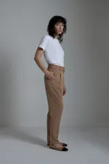 Pantalón de vestir color tostado, de corte recto, con pinzas delanteras, bolsillos laterales y cinturón con hebilla forrada.