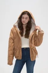 Campera de poliéster color tostado con capucha, cierre frontal con botones a presión y bolsillos delanteros amplios. El interior está forrado con corderito para mayor abrigo.