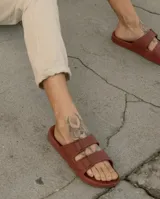 Sandalias planas color ladrillo, con doble tira ancha sobre el empeine y plantilla anatómica. Fabricadas en Brasil con materiales veganos y procesos sostenibles.