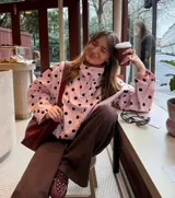 Chaqueta liviana de color rosado con estampado de lunares negros, cuello alto, cierre frontal con broches y cordón ajustable en la cintura. Presenta un calce relajado y puños regulables.