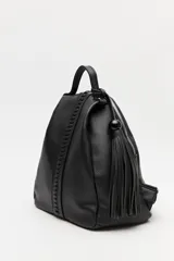 Mochila de símil cuero texturizado color beige, con asa superior, tiras regulables para la espalda y cierre principal metálico. Presenta un detalle trenzado vertical en el frente y un accesorio con flecos y cuenta negra en el lateral.