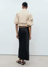 Falda midi evasé de tejido satinado color negro, con tiro medio y cintura elástica sin cierre.