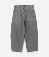 Pantalón de jean estilo baggy balloon, de corte holgado con volumen en las piernas y cintura fija con trabillas. Presenta costuras a contratono y detalle de cadena metálica lateral.