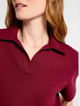 Remera tipo polo de manga corta en color bordeaux, confeccionada en tejido piqué, con cuello clásico y escote en V sin botones. Presenta un pequeño logo bordado en el pecho.