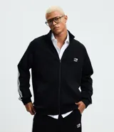 Campera deportiva de cuello alto con cierre frontal, confeccionada en tejido técnico con rayas laterales contrastantes y bordado localizado en el pecho.