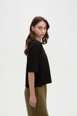 Remera blanca de manga corta, con cuello redondo a la base y diseño holgado.