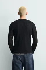 Jersey negro de corte relaxed fit, con estructura de tejido abierto, cuello redondo amplio y manga larga.