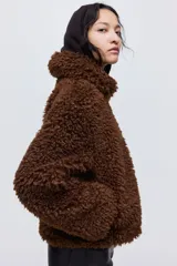 Campera de textura tipo sherpa en color marrón, con cuello clásico, cierre frontal y diseño de corte recto.