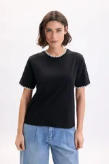 Camiseta de manga corta negra con detalles de pespuntes blancos en contraste en el cuello redondo y en los bordes de las mangas.