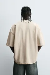 Camiseta color caqui de corte holgado, con cuello redondo y mangas cortas. Acabado con efecto lavado y ruedo irregular.