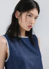 Top de algodón estilo denim, de corte recto y sin mangas con tirantes anchos, cuello redondo y detalle de ribetes contrastantes con costuras decorativas blancas en los bordes.