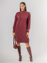 Vestido tipo polerón de tejido de punto color borgoña, con cuello alto, mangas largas con puños ajustados y corte recto. Incluye un cinturón del mismo material con una hebilla decorativa de flor con cristales.