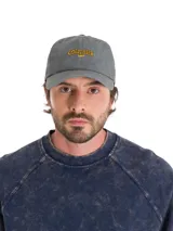 Gorro tipo baseball gris con efecto lavado, con el logo de Caterpillar bordado en amarillo en la parte frontal. Cuenta con visera curva y cierre metálico ajustable en la parte trasera.