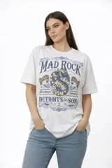 Remera de algodón de manga corta y cuello redondo, con diseño holgado y estampado frontal con motivos florales y texto.