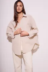 Camisa oversize color arena con rayas verticales marrones, de manga larga y cuello clásico.