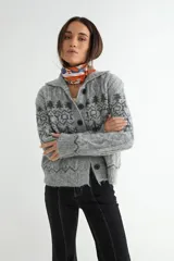 Saco de punto gris con diseño jacquard, cuello tipo polo y cierre frontal con botones negros. Presenta detalles de trenzas en el tejido y puños acanalados.