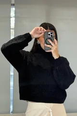 Buzo de chenille color blanco, con cuello alto tipo polera, mangas largas con puños ajustados y diseño de tejido acanalado.