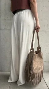 Pantalón palazo de lino color beige, de calce amplio y fluido, con tablas en el frente, botón, cierre y cordón ajustable en la cintura.