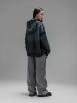 Hoodie oversize de corte crop en color gris oscuro, confeccionado en algodón rústico. Presenta un diseño con costuras expuestas, efecto de desgaste y detalles de roturas en los bordes, incluyendo puños y ruedo.