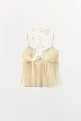 Top de viscosa color beige con diseño de corte evasé y detalle de godets. Presenta un cuello halter de encaje a tono y tirantes finos, con cierre de botones forrados en la parte posterior del cuello.