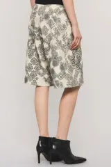 Bermuda de gabardina de calce relajado, tiro largo, con estampado estilo paisley en tonos beige y negro, y bolsillos delanteros estilo cargo con broches metálicos.