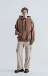 Hoodie oversize de frisa premium color cañamo (marrón claro/beige), con capucha ajustable, bolsillo canguro y puños elastizados con orificios para los pulgares.