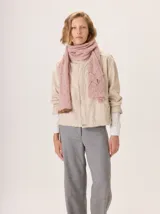 Bufanda gruesa de lana, color rosa claro con motas rosadas y blancas, tejida con punto grueso y textura afelpada.