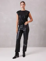 Blusa de lentejuelas color negro, con cuello a la base, sin mangas y detalle de nudo en el ruedo.