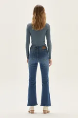 Polera de manga larga con cuello alto, confeccionada en tejido de punto acanalado con diseño de rayas horizontales en color marrón y turquesa. Presenta un bordado pequeño en el pecho y un calce ajustado al cuerpo.