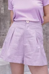 Bermuda a cuadros lila y blanco, de corte holgado y tiro alto, con pinzas y botón a la vista.