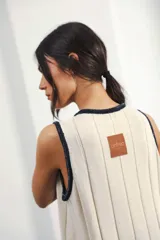 Vestido midi tejido en punto canalé negro con detalles en lurex plateado. Presenta calado artesanal en el ruedo, abertura lateral y etiqueta de cuero en la parte trasera del cuello.