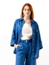 Camisa azul de lino con mangas 3/4, cuello clásico, cierre frontal con botones y bolsillo en el pecho.