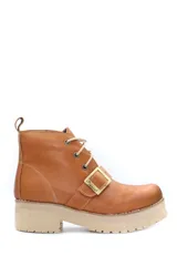 Borcego de cuero color tostado con cordones y detalle de hebilla metálica lateral. Presenta suela track de goma color beige.