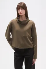 Buzo de cuello alto tipo polera, color verde oliva, con corte holgado, mangas largas y un bolsillo frontal aplicado en el pecho.