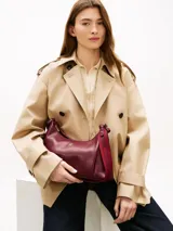 Cartera tipo hobo de Tommy Hilfiger en color bordó, confeccionada en poliuretano con acabado liso. Cuenta con compartimento principal con cierre de cremallera, bolsillo interior con cierre, asa superior y correa ajustable y extraíble. Presenta el logo metálico de la marca en relieve en la parte delantera y detalles en herrajes dorados.